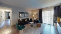 Located at 760 Chapman Dr in Colorado Springs, CO, this single-floor residence offers a thoughtfully designed layout with modern finishes and a cohesive contemporary aesthetic throughout. The living room serves as a welcoming centerpiece, featuring durable wood-look flooring, a sliding glass door that invites natural light, and ample space for comfortable seating arrangements. A dedicated accent wall area showcases bold artwork alongside a rich walnut-toned media console, adding character to the space. The galley-style kitchen is well-equipped with dark wood cabinetry, granite-look countertops, a geometric tile backsplash, stainless steel appliances, and track lighting overhead. An adjacent dining nook provides space for casual meals. The primary bedroom is generously sized with plush carpeting, room for a full furniture suite, and direct access to a hallway leading to the bathroom. The bathrooms feature wood-look flooring, granite vanity tops, dark wood cabinetry, and a tiled tub-shower combination with a decorative vertical tile accent. A versatile secondary room offers carpet flooring and a window with natural light, suitable as a bedroom or home office. Throughout, the space maintains a neutral color palette accented by curated décor, creating a warm and inviting atmosphere.