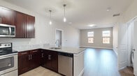 This 2-bedroom, 2-bathroom residence is laid out across a single floor, offering a functional and modern living environment. The open-concept kitchen and living area serves as the heart of the home, featuring rich dark-wood cabinetry, granite countertops, and a peninsula island ideal for dining or entertaining. Stainless steel appliances — including a refrigerator, range, microwave, and dishwasher — complement the kitchen's contemporary aesthetic. Sleek pendant lighting hangs above the island, adding a stylish focal point. The living area flows seamlessly from the kitchen, benefiting from multiple windows that invite natural light and views of the surrounding neighborhood.

Wood-style flooring extends throughout the main living spaces and bedrooms, providing a cohesive and easy-to-maintain surface. The primary bedroom is generously sized, featuring a bank of windows that flood the room with natural light, along with a dedicated closet equipped with wire shelving. The second bedroom is well-proportioned with its own window and closet access. Both bathrooms are finished consistently with granite-topped dark-wood vanities, framed mirrors, and tub/shower combinations. The neutral warm-gray wall palette throughout creates a clean, modern ambiance suitable for a variety of décor styles.