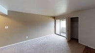 This single-floor residence offers a practical and comfortable layout designed for everyday living. The open living area is finished with neutral-toned carpet and flows seamlessly toward the kitchen, which is accessible via a half-wall pass-through. The kitchen features warm wood cabinetry, white appliances including a refrigerator, electric range, and an under-cabinet range hood, along with parquet-style flooring that adds a classic touch. A stacked washer and dryer unit is also conveniently included within the unit.

The space includes two bedrooms, both carpeted and finished in soft neutral tones. The primary bedroom benefits from a sliding glass door that opens to a private balcony, bringing in natural light and outdoor access. It also includes a sliding-door closet. The second bedroom is equally well-proportioned and features its own walk-in closet, providing ample storage. The bathroom is equipped with a full tub-and-shower combination, complete with a built-in recessed shelf, chrome fixtures, and a curtain rod — offering a clean and functional design. Throughout the unit, the neutral color palette and consistent finishes create a cohesive and inviting atmosphere.