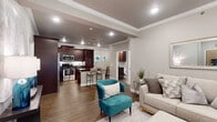 This single-story residence showcases a thoughtfully designed open-concept floor plan that seamlessly connects the living, dining, and kitchen areas. Warm hardwood-style flooring, crown molding, and recessed lighting are consistent throughout, lending a cohesive and polished feel to the entire space.

The living area is anchored by a marble-surround fireplace with a wall-mounted television above, complemented by a ceiling fan and access to an outdoor area through large shuttered glass doors. The kitchen is a standout feature, offering rich dark espresso cabinetry, dark granite countertops, a white subway tile backsplash, stainless steel appliances, and a central island with a double undermount sink and bar seating — ideal for both cooking and casual dining.

The primary bedroom is generously proportioned, featuring a ceiling fan, crown molding, and a direct en suite connection. The primary bathroom is well-appointed with a granite-surround soaking tub, a frameless glass walk-in shower, dark wood vanity cabinetry, and granite countertops. An additional bedroom and full bathroom provide comfortable accommodations for guests, with the second bath also featuring a soaking tub and glass shower combination. Neutral gray tones throughout create a calm, contemporary ambiance.
