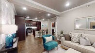 This single-story residence showcases a thoughtfully designed open-concept floor plan that seamlessly connects the living, dining, and kitchen areas. Warm hardwood-style flooring, crown molding, and recessed lighting are consistent throughout, lending a cohesive and polished feel to the entire space.

The living area is anchored by a marble-surround fireplace with a wall-mounted television above, complemented by a ceiling fan and access to an outdoor area through large shuttered glass doors. The kitchen is a standout feature, offering rich dark espresso cabinetry, dark granite countertops, a white subway tile backsplash, stainless steel appliances, and a central island with a double undermount sink and bar seating — ideal for both cooking and casual dining.

The primary bedroom is generously proportioned, featuring a ceiling fan, crown molding, and a direct en suite connection. The primary bathroom is well-appointed with a granite-surround soaking tub, a frameless glass walk-in shower, dark wood vanity cabinetry, and granite countertops. An additional bedroom and full bathroom provide comfortable accommodations for guests, with the second bath also featuring a soaking tub and glass shower combination. Neutral gray tones throughout create a calm, contemporary ambiance.