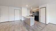 Located at 7412 E 26th St in Sioux Falls, SD, this one-bedroom, one-bathroom unit offers a well-designed, efficient layout across a single floor. The open-concept living, dining, and kitchen area serves as the heart of the home, featuring wood-look plank flooring, neutral white walls, and a ceiling fan that enhances airflow and comfort. A sliding glass door leads to a private balcony, allowing natural light to filter into the living space.

The kitchen is equipped with a peninsula breakfast bar, gray cabinetry, light countertops, a double-basin sink, and black appliances including a refrigerator, range, and microwave. Ample cabinet storage and a practical galley-style layout make the kitchen highly functional.

The bedroom is a calm, carpeted retreat featuring a large window with natural light and outdoor views, along with three closets providing generous storage options.

The combined bathroom and laundry room is a standout feature, offering a vanity with a stone-patterned countertop, a large mirror, and the convenience of in-unit washer and dryer hookups — all within one well-appointed space.

Throughout the unit, dark wood-toned door trim adds a warm contrast to the bright, clean walls, creating a cohesive and modern aesthetic.