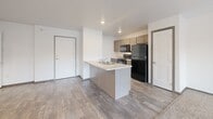 Located at 7412 E 26th St in Sioux Falls, SD, this one-bedroom, one-bathroom unit offers a well-designed, efficient layout across a single floor. The open-concept living, dining, and kitchen area serves as the heart of the home, featuring wood-look plank flooring, neutral white walls, and a ceiling fan that enhances airflow and comfort. A sliding glass door leads to a private balcony, allowing natural light to filter into the living space.

The kitchen is equipped with a peninsula breakfast bar, gray cabinetry, light countertops, a double-basin sink, and black appliances including a refrigerator, range, and microwave. Ample cabinet storage and a practical galley-style layout make the kitchen highly functional.

The bedroom is a calm, carpeted retreat featuring a large window with natural light and outdoor views, along with three closets providing generous storage options.

The combined bathroom and laundry room is a standout feature, offering a vanity with a stone-patterned countertop, a large mirror, and the convenience of in-unit washer and dryer hookups — all within one well-appointed space.

Throughout the unit, dark wood-toned door trim adds a warm contrast to the bright, clean walls, creating a cohesive and modern aesthetic.