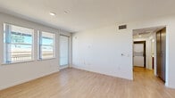 Located on Westwind Street in Livermore, California, this one-bedroom, one-bathroom residence offers a thoughtfully designed single-floor layout with a clean, modern aesthetic. The open-concept living and kitchen area is bright and welcoming, featuring light wood-tone laminate flooring, white walls, and a sliding glass door that invites natural light and outdoor views. The kitchen is well-appointed with warm wood-grain cabinetry extending to the ceiling, white quartz countertops, stainless steel appliances including a refrigerator, range, microwave, and dishwasher, plus a stainless steel sink — all combining function with contemporary style. A hallway connects the main living area to the private bedroom, which is carpeted and bathed in natural light from a trio of windows overlooking the outdoors. The bedroom includes a walk-in closet outfitted with wire shelving for ample storage. The bathroom features light wood-tone cabinetry, a white countertop vanity, and light wood-look flooring, maintaining the cohesive modern palette found throughout the home. Recessed lighting, ceiling vents, and clean white finishes complete the polished, move-in-ready feel of this residence.