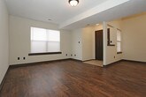 This two-floor space offers a functional and cohesive design defined by a consistent use of dark trim, dark cabinetry, and neutral wall tones throughout. The main level features a spacious living and dining area finished with rich, dark wood-style plank flooring that extends toward the entryway. A staircase with carpeted treads connects to the upper level, and a pass-through opening provides a visual connection between the living area and kitchen.

The kitchen is equipped with dark espresso cabinetry, dark speckled countertops, a double stainless steel sink, a dishwasher, and a stainless steel range. Light tile flooring complements the cabinetry, and a window provides natural light to the space.

The upper level hosts multiple carpeted bedrooms, each featuring windows with blinds, closet access, and neutral walls beneath a textured ceiling. The bedrooms share access to bathrooms appointed with dark cabinetry, speckled countertops, tile flooring, large vanity mirrors, and overhead lighting. One bathroom includes a full tub-shower combination. Throughout both floors, dark door and baseboard trim provides a unifying design element.