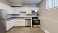 Located at 127 Michael Road in New London, CT, this four-bedroom, one-bathroom unit offers a practical and well-appointed single-floor layout. The kitchen is a standout feature, showcasing white shaker-style cabinetry, granite countertops, wood-look flooring, and a full suite of stainless steel appliances including a range, microwave, and dishwasher. The space is efficiently designed to maximize functionality.

The four bedrooms are finished with neutral gray walls and plush carpeting, creating a comfortable and cohesive feel throughout. Several bedrooms feature windows that invite natural light and outdoor views of the surrounding greenery. The generously sized primary bedroom provides ample room, while the additional bedrooms offer flexible use for various needs. At least one bedroom includes a double-panel closet, providing practical storage solutions.

The bathroom is clean and bright, featuring a full tub-shower combination, a white vanity with medicine cabinet, and wood-look flooring that ties in with the rest of the unit. Baseboard heating is present throughout the rooms, ensuring consistent warmth. A hallway connects the living spaces efficiently, completing this straightforward and functional floor plan in a convenient New London location.