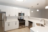 Located at 2800 New Brunswick Ave in Piscataway, NJ, this single-floor residence offers a clean, modern design with a neutral color palette throughout. The open-concept living and dining area features light hardwood-style flooring and flows seamlessly into a well-appointed kitchen. The kitchen is outfitted with crisp white cabinetry accented by matte black hardware, a classic white subway tile backsplash, light quartz countertops, and stainless steel appliances including a gas range, over-the-range microwave, and dishwasher. Pendant lighting adds a contemporary touch above the kitchen peninsula. The bedrooms are carpeted in a neutral tone and receive ample natural light through blinds-fitted windows, lending a calm and comfortable atmosphere. The space includes two full bathrooms, both finished with light tile flooring and white vanities. One bathroom features a tub-shower combination, while the other offers a frameless glass-enclosed walk-in shower with tile surround. A dedicated in-unit laundry room houses a full-size washer and dryer with overhead shelving for added storage convenience. The overall design is bright, clean, and move-in ready, reflecting a contemporary residential aesthetic.
