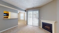 Located at 4415 Heritage Ave in Okemos, Michigan, this single-floor residence offers a well-organized layout with a comfortable and functional design throughout. The living room serves as the heart of the home, featuring plush carpeting, a classic fireplace with a white mantel, and full-height sliding glass doors framed by vertical blinds that fill the space with natural light and provide direct access to the outdoors. A pass-through opening connects the living area to the kitchen, creating an open and communicative flow between spaces. The kitchen is equipped with wooden cabinetry, a refrigerator, electric range, and a sink, all set atop wood-look flooring that adds warmth to the functional space. A bedroom offers generous natural light through dual windows overlooking the surrounding trees, paired with soft carpeting for a restful atmosphere. The bathroom features a wide vanity with warm oak cabinetry, a single-basin sink, and a well-lit mirror. A dedicated laundry room provides added convenience with a full-size washer and dryer, wire shelving for storage, wood-look flooring, and an electrical panel and water heater housed within the same space. The textured ceilings throughout add a consistent architectural detail across the home.