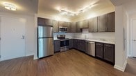 This single-floor, two-bedroom, one-and-a-half-bathroom residence offers a well-organized layout with a cohesive modern design throughout. The kitchen serves as a functional centerpiece, featuring dark espresso cabinetry, marble-style countertops, and a full suite of stainless steel appliances including a refrigerator, range, microwave, and dishwasher. Track lighting overhead illuminates the space effectively, and rich hardwood-style flooring extends through the kitchen and living areas, adding warmth and visual continuity.

The living area is open and airy, with neutral walls, hardwood-style flooring, and a window that allows natural light to fill the room. Both bedrooms are carpeted and finished with neutral tones, each featuring a generously sized window fitted with blinds, providing natural light and outdoor views.

The full bathroom includes a tub-shower combination, tile flooring, a dark-cabinetry vanity with a stone-style countertop, and chrome fixtures. The half bathroom mirrors the full bath's aesthetic, with matching tile flooring, a dark vanity, and stone countertop. Together, the rooms present a clean, modern, and functional living environment.