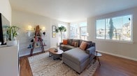 This thoughtfully designed single-floor residence offers a cohesive blend of modern finishes and comfortable living spaces. The kitchen is a standout feature, showcasing rich dark cabinetry paired with crisp white countertops, a central island ideal for meal prep or casual dining, and a full suite of stainless steel appliances including a refrigerator, range, microwave, and dishwasher. Warm hardwood-style flooring and pendant lighting add a polished, contemporary feel to the space. The open layout flows naturally into a dining area and into the living room, which is bathed in natural light from generously sized windows. The living room centers around a sleek fireplace, creating a welcoming focal point, and offers ample space for relaxed seating arrangements. The bedroom is a calm and restful retreat, featuring plush carpeting, natural light from multiple windows with blinds, and a neutral color palette that promotes a serene atmosphere. The bathroom is finished with dark cabinetry, a dual-sink vanity with white countertops, hardwood-style flooring, and a full soaking tub with shower. Clean lines and consistent finishes throughout the unit create a unified and refined living environment.