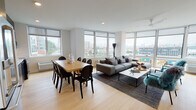 Located at 7601 River Road in North Bergen, NJ, this modern residence offers a thoughtfully designed single-floor layout with contemporary finishes and abundant natural light. The open-concept living and dining area is a standout feature, wrapped in expansive floor-to-ceiling windows that frame sweeping views of the surrounding urban landscape. Light hardwood flooring flows throughout, complementing the bright, neutral palette of the interior.

The kitchen is outfitted with sleek, flat-front cabinetry in a sophisticated gray tone, white quartz countertops, a subway tile backsplash, and stainless steel appliances, delivering a clean, modern aesthetic. The living area accommodates both a dining space and a generous lounge area, enhanced by a ceiling fan and recessed lighting.

The unit features two well-proportioned bedrooms, each with light wood floors, large windows offering neighborhood views, and ample room for storage. One bedroom benefits from corner window placement, further maximizing natural light.

The bathrooms are finished with large-format stone-look tile on both floors and walls. The primary bathroom includes a frameless glass walk-in shower, while the secondary bathroom offers a full soaking tub with a multi-function shower system, warm wood cabinetry, and an integrated vanity.