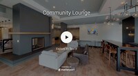 Located at 247 Chicago Ave in Minneapolis, MN, this contemporary single-floor amenity space is thoughtfully designed to serve as a dynamic social and gathering hub. The open-concept layout is anchored by a spacious lounge area furnished with generous sectional sofas, accent chairs, and ottomans, all set atop warm hardwood-style flooring. A bold, floor-to-ceiling dark accent wall frames a sleek built-in fireplace, creating an inviting focal point for relaxed conversation and entertaining.

Adjacent to the lounge, a dining and bar-height seating area benefits from expansive floor-to-ceiling windows that bathe the space in natural light while offering views of the surrounding neighborhood. Pendant and chandelier lighting adds a refined ambiance throughout. A wall-mounted flat-screen TV and additional lounge seating extend the entertainment options, while a regulation billiards table provides recreational appeal in a dedicated game area.

The space also features a well-appointed catering kitchen equipped with stainless steel appliances, including a gas range with hood, side-by-side refrigerator, double sink, and open wood shelving alongside cabinetry for ample storage. Wide corridors connect all areas seamlessly, with accessible restroom facilities conveniently located nearby. The overall design balances modern aesthetics with functional versatility.