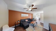 Located at 1980 W Main St in Central, SC, this two-story, 2-bedroom, 3-bathroom home offers a practical and well-organized layout spread across two floors. The main level features rich wood-style flooring throughout the living room, kitchen, and bathrooms. The living room makes a bold visual statement with a warm terracotta accent wall, ceiling fan, and ample space for relaxing or working. The kitchen is appointed with white cabinetry, granite-look countertops, white appliances including a range and microwave, and a double sink — all bathed in natural light from a rear entry door with a glass panel. A dedicated laundry area with a full-size washer and dryer is conveniently located on the main floor alongside the refrigerator. Three bathrooms serve the home, including one with a shower/tub combo. Upstairs, both bedrooms offer carpet flooring, ceiling fans, and natural light from windows with blinds. The primary bedroom provides a comfortable, well-proportioned retreat, while the second bedroom features additional desk space suitable for a home office setup. The home's neutral color palette and clean finishes create a bright, move-in-ready atmosphere throughout.