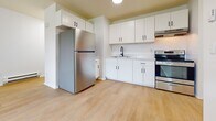 Located at 700 Justine Court in Bay Shore, New York, this 540 sq ft single-floor, 1-bedroom apartment offers a clean, modern layout. The kitchen features white shaker cabinets with matte black hardware, marble-style countertops, a stainless steel refrigerator, electric range, and a black-accented sink. Light wood flooring flows throughout the unit. The 150 sq ft bedroom includes a ceiling fan, large windows for natural light, and baseboard heating. The open living area is bright and functional, complemented by two closets for ample storage.