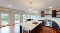Located at 4264 Upton Ave S in Minneapolis, this single-floor residence showcases a thoughtfully designed open-concept layout with high-end finishes throughout. The kitchen serves as a central highlight, featuring rich dark-wood cabinetry, white quartz countertops, a subway tile backsplash, stainless steel appliances including a professional-grade gas range, and a spacious island with an undermount sink and built-in wine rack. Two striking crystal chandelier pendants anchor the kitchen and flow seamlessly into the open living area, which is bathed in natural light from a bank of large windows and a glass door leading to a private outdoor deck with treetop views.

Polished hardwood floors extend throughout the main living spaces, while bedrooms feature plush carpeting, tray ceilings, ceiling fans, and generous windows framing lush outdoor scenery. The primary bathroom is appointed with a dual-sink vanity, a glass-enclosed walk-in shower with tile surround, and a soaking tub. A secondary bathroom offers a single vanity and glass-enclosed shower. The entry hall connects all spaces efficiently, contributing to the unit's clean, modern, and cohesive overall ambiance.