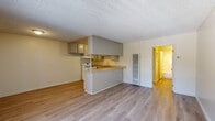 Located at 10210 Mountair Avenue in Tujunga, CA, this one-bedroom, two-bathroom unit offers a practical and well-organized single-floor layout. The living room features light wood-style flooring, a textured ceiling, a wall-mounted air conditioning unit, and a large window with vertical blinds that allows natural light to fill the space. Adjacent to the living area is a dedicated dining space that flows seamlessly into the kitchen. The kitchen is equipped with gray cabinetry extending to the ceiling for ample storage, a white gas range, a double-basin sink, and light-toned countertops. A peninsula counter separates the kitchen from the living and dining areas, creating an open yet defined layout. The bedroom is carpeted and features a sliding mirrored closet, a window with vertical blinds, and a textured ceiling, offering a quiet and comfortable retreat. A hallway connects the main living areas to both bathrooms; one bathroom includes a shower/tub combo with sliding glass doors and wood-style flooring, while the second bathroom provides additional convenience. The unit's neutral color palette, consistent flooring, and functional design make for a clean and practical living environment.