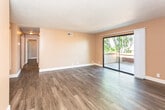 Located at 4217 Louisiana Blvd NE in Albuquerque, New Mexico, this single-floor unit offers a well-organized layout with consistent finishes throughout. Dark hardwood-style flooring runs through the main living areas and bedrooms, providing a cohesive and modern aesthetic that contrasts with the warm, neutral-toned walls.

The living area is generously sized, featuring a textured ceiling, ceiling-mounted HVAC vents, and a full-width sliding glass door that opens to an outdoor space and allows natural light to fill the room. The open sightlines from the living area connect to a hallway leading to the bedrooms.

The galley-style kitchen is efficiently designed with white cabinetry on both sides, under-cabinet lighting, a double sink, and black appliances including a gas range and refrigerator. The layout maximizes counter and storage space within a compact footprint.

The bedrooms are well-proportioned, each featuring dark hardwood-style floors, warm-toned walls, vertical blind-covered windows that bring in natural light, and textured ceilings. The bathroom is clean and functional, showcasing dark cabinetry with granite-style countertops, a single-basin sink, and a towel bar. The textured wall finish adds a subtle design detail throughout the wet areas of the unit.