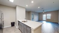 This contemporary apartment, located at The Quarters At Towson Town Center in Baltimore, offers a spacious 1090 square feet of living area on a single floor. The layout comprises two bedrooms, including a primary bedroom of 180 square feet, and two full bathrooms. The open-concept design seamlessly integrates two living room areas with the kitchen, creating a fluid and versatile space.

The apartment boasts modern finishes throughout, with a neutral color palette and durable wood-look flooring. The kitchen features sleek gray cabinetry, stainless steel appliances, and a convenient island with a white countertop. Both bathrooms are equipped with stylish vanities, large mirrors, and glass-enclosed showers.

Natural light floods the space through multiple windows, some adorned with blinds for privacy control. The bedrooms are generously sized, with the second bedroom offering flexibility as a guest room or home office. Two closets provide ample storage space, with one walk-in closet showcasing built-in shelving systems.

Additional amenities include a ceiling fan in the living area for improved air circulation and recessed lighting throughout. The apartment's layout and design cater to modern living, offering both comfort and functionality in an urban setting.