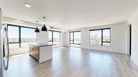 Located at 1300 40th St in Denver's vibrant Cole neighborhood, this modern 2-bedroom, 2-bathroom residence delivers a refined urban living experience. The open-concept kitchen and living area is the heart of the home, showcasing large black-framed windows that frame sweeping views of the Denver skyline and surrounding cityscape, flooding the space with abundant natural light. The kitchen is outfitted with warm wood cabinetry, a bold blue tile backsplash, stainless steel appliances, dark countertops, a central island with pendant lighting, and hardwood-style flooring that extends throughout the main living areas. The generously sized primary bedroom features plush carpeting, a ceiling fan, and a large window with outdoor views. Its en-suite bathroom includes warm wood vanity cabinetry, dark countertops, and direct access to a spacious walk-in closet with built-in shelving. The second bedroom is bright and well-proportioned, also carpeted with a ceiling fan. A convenient in-unit stacked washer and dryer is tucked behind a dedicated closet. Two closets provide ample storage throughout. The clean, contemporary palette of white walls, light flooring, and black hardware details creates a cohesive, modern aesthetic throughout this well-appointed Denver residence.
