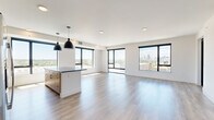 Located at 1300 40th St in Denver's vibrant Cole neighborhood, this modern 2-bedroom, 2-bathroom residence delivers a refined urban living experience. The open-concept kitchen and living area is the heart of the home, showcasing large black-framed windows that frame sweeping views of the Denver skyline and surrounding cityscape, flooding the space with abundant natural light. The kitchen is outfitted with warm wood cabinetry, a bold blue tile backsplash, stainless steel appliances, dark countertops, a central island with pendant lighting, and hardwood-style flooring that extends throughout the main living areas. The generously sized primary bedroom features plush carpeting, a ceiling fan, and a large window with outdoor views. Its en-suite bathroom includes warm wood vanity cabinetry, dark countertops, and direct access to a spacious walk-in closet with built-in shelving. The second bedroom is bright and well-proportioned, also carpeted with a ceiling fan. A convenient in-unit stacked washer and dryer is tucked behind a dedicated closet. Two closets provide ample storage throughout. The clean, contemporary palette of white walls, light flooring, and black hardware details creates a cohesive, modern aesthetic throughout this well-appointed Denver residence.