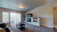 This single-floor residence in Kansas City, Missouri offers a thoughtfully designed layout with comfortable living spaces and quality finishes throughout. The living room serves as the centerpiece of the home, featuring plush carpeting, a tile-surround fireplace flanked by built-in shelving, and a sliding glass door with vertical blinds that opens to a private balcony, allowing natural light to fill the space. Adjacent to the living area, the dining space accommodates a dark wood table and chairs beneath a brushed nickel chandelier, with wood-style flooring that continues into the kitchen. The kitchen is well-equipped with white cabinetry, granite countertops, stainless steel appliances including a refrigerator, range, and over-the-range microwave, and a functional island with an undermount sink. The bedroom is a comfortable retreat featuring carpet flooring, a ceiling fan, and a window that brings in natural light. The bathroom includes a white vanity with granite countertop, a large mirror with contemporary lighting, and wood-style flooring, with an in-unit laundry area conveniently nearby. Neutral wall tones and consistent finishes create a cohesive and inviting atmosphere throughout the home.