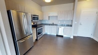 This contemporary 2-bedroom, 2-bathroom unit is thoughtfully designed across a single floor, offering a clean, modern aesthetic throughout. The open-concept living area features dark hardwood-style flooring and neutral gray walls, creating a sleek and cohesive feel. A sliding glass door floods the living space with natural light and provides direct outdoor views of the surrounding cityscape.

The kitchen is efficiently laid out with light wood cabinetry, dark countertops, and a full suite of stainless steel appliances, including a refrigerator, electric range, over-the-range microwave, and dishwasher. The design balances functionality with style, making it an ideal space for everyday cooking.

Both bedrooms offer dark hardwood-style flooring and large windows that invite abundant natural light and offer views of the exterior surroundings. The rooms provide comfortable proportions suited for rest or flexible use.

Each of the two bathrooms features a modern vanity with a dark countertop, undermount sink, framed mirror with contemporary lighting fixtures, and built-in open shelving for added storage. The overall design of the unit emphasizes clean lines, practical storage solutions, and a consistent modern palette throughout every room.