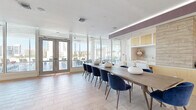 Located at 1400 Fruitville Rd in downtown Sarasota, Florida, this single-floor amenity space offers a thoughtfully designed and generously sized interior that blends modern aesthetics with vibrant, social functionality. The layout flows seamlessly across its various areas, beginning with an open living room anchored by a wall-mounted display, a sleek linear fireplace, and a distinctive whitewashed wood column that adds warmth and texture to the bright, neutral palette.

The game room is a standout feature, housing two full-size pool tables set atop a bold, multicolored geometric area rug. Dramatic chandelier lighting and floor-to-ceiling glass walls fill the space with natural light while offering sweeping views of the Sarasota skyline and an outdoor terrace complete with lounge seating.

A dedicated dining area accommodates large groups at a long communal table surrounded by navy velvet chairs, adjacent to the full kitchen. The kitchen is outfitted with warm wood cabinetry, a stainless steel refrigerator, tile backsplash, and a broad white quartz island. Light wood-tone tile flooring runs throughout, tying the entire space together. Additional seating nooks and a glass-enclosed private room provide flexible spaces for quieter gatherings or focused use.