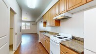 Located at 850 E Jones Ave in Phoenix, AZ, this single-floor unit offers a practical and efficient layout across a compact footprint. The open-plan kitchen and living area form the heart of the space, featuring warm-toned wood-look flooring that extends throughout. The kitchen is well-equipped with ample honey-toned cabinetry — including both upper and lower cabinets with open shelving accents — dark granite-style countertops, a coil-burner electric range, a refrigerator, a sink, and an overhead ventilation hood. A peninsula-style counter provides additional workspace and subtle separation between the kitchen and living zones. The living area is bright and open, benefiting from a sliding window that frames a view of surrounding greenery, and is served by a wall-mounted split A/C unit for climate control. A hallway connects the main living space to the bathroom and entry door. The bathroom features light ceramic tile flooring, a pedestal sink, a mirrored medicine cabinet, a toilet, and a tiled shower. A closet with sliding doors offers convenient storage. Clean white walls and consistent flooring throughout contribute to a cohesive, functional atmosphere suited for everyday living in the heart of Phoenix.