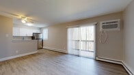 This single-floor residence offers a thoughtfully designed layout with a clean, modern aesthetic throughout. The open-concept living and dining area is finished with light hardwood-style flooring and neutral warm-toned walls, creating a bright and welcoming atmosphere. A full-width sliding glass door floods the space with natural light and opens to a private balcony overlooking a lush, wooded setting. A wall-mounted air conditioning unit and baseboard heating ensure year-round comfort.

The kitchen is well-equipped with crisp white shaker cabinetry, granite countertops, a subway tile backsplash, and a full suite of stainless steel appliances including a refrigerator, range, microwave, and dishwasher. A double-basin undermount sink with a brushed nickel faucet completes the functional workspace.

A connecting hallway with light hardwood-style flooring leads to the bedrooms, each carpeted for comfort and featuring ceiling fans, natural light, and generous closet space. The bathroom is finished with classic white subway tile wainscoting, a white vanity, and clean, timeless fixtures. Additional closet storage is available near the entry, which also provides convenient access throughout the home.