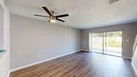 Located at 4704 Lucier Ct in Winter Park, Florida, this two-story home offers a thoughtfully designed layout across two well-proportioned floors. The main level features a bright, open living area finished with rich wood-look flooring and a contemporary ceiling fan, with sliding glass doors that flood the space with natural light and provide direct access to a private patio with outdoor views. The kitchen is clean and functional, showcasing white cabinetry, light quartz countertops, a subway tile backsplash, a double-basin sink, and stainless steel appliances including a dishwasher and refrigerator. A pass-through opening connects the kitchen to the living area, enhancing the open feel. The home includes three bedrooms, each featuring wood-look flooring, ceiling fans, and windows with natural light. The primary bedroom offers a generous footprint with ample space. Five well-organized closets — some with wire shelving systems — provide practical storage throughout. The three bathrooms feature neutral tones with granite-topped vanities. A staircase connects both floors, with a hallway facilitating easy circulation. The overall ambiance is clean, modern, and move-in ready, suited to comfortable everyday living in a quiet Winter Park setting.