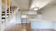 Located at 2315 Muirwood Dr in Columbus, Ohio, this two-story home offers 2 bedrooms and 2 bathrooms across two well-defined floors. The main level provides generous living space, featuring warm wood-look flooring, exposed ceiling beams, and a textured ceiling that adds character to the open layout. A white-railed staircase with a classic design connects the two floors and serves as a functional architectural focal point. The kitchen is thoughtfully equipped with white cabinetry, a full suite of white appliances including a range, dishwasher, and refrigerator, and a peninsula countertop that creates a natural division between the kitchen and living areas. Pendant and flush-mount lighting illuminate the space efficiently. Upstairs, both bedrooms feature plush carpeting, soft neutral wall tones, and ceiling fans with integrated lighting. Each bedroom benefits from natural light through windows with blinds, and the primary bedroom includes dual closets for ample storage. The bathrooms are clean and functional, with one featuring a full tub/shower combination and the other offering a long vanity with white cabinetry and a large mirror. Wood-look flooring in the bathrooms complements the main level finishes, creating a cohesive aesthetic throughout the home.