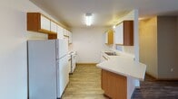 Located at 3570 42nd St S in Fargo, North Dakota, this single-floor unit offers a well-organized and practical layout suited for everyday living. The kitchen is equipped with ample wood-trimmed cabinetry in both white and warm oak tones, a full suite of white appliances including a refrigerator and electric range, a sink with countertop workspace, and durable wood-look flooring that extends into the adjacent living and dining areas. A pendant light fixture anchors the dining space, which also features convenient closet storage and direct access to the entry door. The living area is spacious and open, with dark wood-look flooring, a textured ceiling, baseboard heating, and direct sightlines to a full bathroom with a vanity and tub-shower combination. Two bedrooms provide comfortable accommodations, each featuring plush carpeting, baseboard heating, a window allowing in natural light, and a textured ceiling. A second full bathroom mirrors the first, offering a vanity with storage, a tub-shower combination, and neutral tile flooring. Throughout the unit, warm wood-toned doors and trim create a cohesive, understated aesthetic. The overall layout is efficient and functional, making this Fargo unit a practical and comfortable living space.