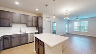 Located at 2401 Stanford Rd in Panama City, FL, this thoughtfully designed single-story residence offers 2 bedrooms and 2 bathrooms across a well-utilized floor plan. Light wood-tone flooring runs throughout, complementing the neutral color palette and creating a cohesive, contemporary feel.

The open-concept kitchen is a standout feature, showcasing rich dark cabinetry, white quartz countertops, a classic subway tile backsplash, and a full suite of stainless steel appliances. A central island with pendant lighting serves as both a prep space and a casual gathering point, flowing seamlessly into the combined dining and living area, which is accented by a modern sputnik chandelier.

The primary bedroom is generously sized, with natural light streaming through windows fitted with blinds and a ceiling fan overhead. Both bedrooms offer access to well-organized closets—five closets are distributed throughout the home. The bathrooms are finished with dark vanity cabinetry, quartz counters, and marble-style tile surrounds in the tub-shower combinations.

Additional spaces include a dedicated laundry room, a welcoming entrance, a hallway, and an outdoor patio. The overall ambiance is clean, modern, and move-in ready.