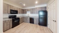 This single-floor unit offers a thoughtfully designed layout that balances comfort and functionality. The kitchen serves as a standout feature, equipped with warm wood-toned cabinetry, granite-style countertops, and a full suite of black appliances including a refrigerator, range, dishwasher, and over-the-range microwave. Light hardwood-style flooring flows through the kitchen and open living area, creating a seamless and bright common space. The living area transitions smoothly from the kitchen, providing an open and airy feel with clean white walls and recessed lighting overhead. Two carpeted bedrooms offer a cozy retreat, each finished with neutral tones, window blinds for privacy, and ample wall space. The unit includes two full bathrooms, each featuring a tub-shower combination, wood-toned vanity with granite countertop, an undermount sink with brushed nickel fixtures, and light wood-look tile flooring. Safety features such as smoke and fire detectors are present throughout. The overall design aesthetic is clean and modern, with a neutral color palette that provides a versatile backdrop well-suited for a variety of interior styles.