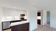 Located at 3700 10th Avenue, Unit 3O in San Diego, this single-floor residence showcases a contemporary design with a thoughtful layout and high-quality finishes throughout. The kitchen is a standout feature, boasting a striking contrast between rich dark wood lower cabinetry and crisp white upper cabinets, all complemented by bright white countertops and a textured tile backsplash. Stainless steel appliances, including a range, microwave, and sink, lend a polished, modern aesthetic. Recessed lighting illuminates the space efficiently, enhancing the clean, bright atmosphere. A peninsula counter provides additional workspace and doubles as a casual dining or entertaining area. Adjacent to the kitchen, a dedicated built-in wine rack and additional dark wood cabinetry offer stylish and functional storage. Light wood-tone flooring runs throughout, adding warmth to the otherwise crisp, modern palette. The overall ambiance is sleek and refined, with an open feel that makes excellent use of the available space, making this unit a well-appointed and contemporary San Diego residence.