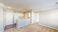 Located at Renaissance Place in Toledo, Ohio, this one-bedroom, one-bathroom residence offers a thoughtfully designed single-floor layout. The open-concept living and kitchen area serves as the heart of the home, where rich hardwood-style flooring in the kitchen transitions seamlessly to soft wall-to-wall carpet in the living space. The kitchen is equipped with white cabinetry, a full suite of appliances including a refrigerator, electric range, and built-in microwave, and features a peninsula with a sink and breakfast bar that opens toward the living area. Track lighting overhead adds a functional yet stylish touch. The bedroom is a comfortable retreat featuring plush carpet, a bold dark accent wall, and multiple windows that flood the room with natural light and offer views of the surrounding community. A sliding glass door in an additional room provides outdoor access and further enhances the sense of openness. The dedicated closet includes wire shelving and hanging rods for organized storage. The bathroom is clean and functional, featuring a full tub-shower combination with tiled surround and hardwood-style flooring. A utility room rounds out the floor plan, providing added practicality to this well-appointed residence.