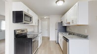 This two-story residence is designed with a clean, functional layout that maximizes comfort and usability across both levels. The main living area is open and airy, featuring light wood-style flooring, neutral walls, and a sliding glass door that invites natural light and provides outdoor access. A ceiling fan adds a practical touch to the living space.

The galley-style kitchen is well-appointed with crisp white shaker cabinetry, brushed nickel hardware, and marbled gray laminate countertops. Stainless steel appliances — including a refrigerator, electric range, over-the-range microwave, and dishwasher — complete the space, which also benefits from light wood flooring and ample upper and lower cabinet storage.

The staircase leads to the upper level, where carpeted bedrooms provide a comfortable, quiet retreat. Each bedroom is generously proportioned with neutral tones and vertical blinds on the windows. One bedroom connects directly to a bathroom, offering added privacy and convenience.

The bathroom is neatly finished with a tiled tub-shower combination, wood-style flooring, and brushed nickel fixtures. Throughout the home, consistent neutral tones, light flooring, and thoughtful built-in storage — including a closet beneath the staircase — contribute to a cohesive and practical living environment.