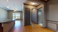 Located at 10 East Archer Street in the heart of downtown Tulsa, Oklahoma, this single-floor residence offers a thoughtfully designed layout with quality finishes throughout. The interior is anchored by warm hardwood flooring that flows through the main living areas, complemented by neutral taupe-toned walls and rich dark wood trim and crown molding details.

The kitchen serves as a central hub of the space, featuring a large island with a double-basin sink and striking dark granite countertops. Rich wood cabinetry extends to the ceiling, providing generous storage, while a full suite of stainless steel appliances — including a refrigerator, range, built-in microwave, and dishwasher — complete the setup. Track lighting overhead adds a modern touch. A conveniently located in-unit laundry area is accessible just off the kitchen.

The living area benefits from natural light through large windows fitted with horizontal blinds, and a ceiling fan adds comfort. Tray ceilings with dark wood detailing lend an architectural elegance to the space. Bedrooms are carpeted for comfort, each with windows that invite natural light. The bathroom is finished with tile flooring, a dark granite vanity, dark wood cabinetry, and a full tub-shower combination.