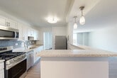 Located at 1220 E West Hwy in Silver Spring, MD, this well-appointed 3-bedroom, 2-bathroom residence offers a thoughtfully designed single-floor layout. The open-concept kitchen is a standout feature, showcasing white shaker cabinetry, granite countertops, a subway tile backsplash, stainless steel appliances including a gas range and dishwasher, and a peninsula with pendant lighting — seamlessly connecting to both the dining and living areas. Wood-style flooring flows through the kitchen and main living spaces, while plush carpeting adds comfort to the bedrooms. The living and dining areas are bright and generously proportioned, providing flexible use of space. The primary bedroom is notably spacious, featuring large windows with urban views, carpet flooring, and access to an expansive walk-in closet with extensive shelving and hanging space. Two additional bedrooms offer the same wood-style flooring and ample closet storage, with a total of seven closets throughout the home. The bathrooms are finished with clean, modern white tile surround tub-shower combinations. A connecting hallway ties the layout together efficiently. The residence provides abundant natural light and views of the surrounding Silver Spring cityscape.