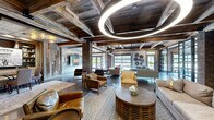 Located at 1015 Nelson Merry St in Nashville, TN, this expansive single-floor space masterfully combines industrial and rustic design elements to create a compelling and versatile environment. The architecture is defined by its striking reclaimed wood ceiling, featuring heavy exposed beams that lend warmth and texture overhead, while ornate pressed-tin ceiling panels in select areas add a refined vintage touch. Exposed brick columns anchor the open floor plan throughout, complementing the highly polished concrete floors that reflect light across the generous interior.

The main gathering area is an expansive, open-plan lounge furnished with multiple modern seating arrangements, layered with patterned area rugs and accented by decorative wall art, including industrial gear motifs and windmill sculptures. Large glass garage-style doors open the space to natural light and outdoor views, reinforcing the airy, loft-like atmosphere. A separate dining or meeting area enclosed by steel-framed glass barn doors provides a versatile private zone without sacrificing visual connectivity.

A more intimate nook features bold patterned wallpaper and a cozy seating arrangement alongside a dartboard, offering a playful retreat within the larger space. Two hallways connect distinct zones efficiently, while circular pendant lighting adds a contemporary focal point. Overall, the space exudes an inviting, eclectic industrial ambiance ideal for community gathering or event use.