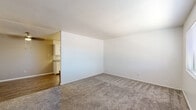 This single-floor residence offers a well-organized layout that balances comfort and functionality throughout its thoughtfully arranged rooms. The living area is generously sized, featuring plush wall-to-wall carpeting, clean white walls, and a textured ceiling that adds subtle dimension. An open sightline connects the living space to the kitchen, creating a cohesive flow between the two areas. The galley-style kitchen is a standout feature, outfitted with crisp white cabinetry, grey laminate countertops, a double basin sink, and stainless steel appliances including an electric range and refrigerator. A decorative geometric tile backsplash adds a modern touch, while wood-look vinyl flooring runs underfoot for easy maintenance. The bedrooms are carpeted and bathed in natural light from horizontal-blind-fitted windows, offering a quiet and comfortable retreat. Each bedroom provides ample open wall space suitable for various furniture arrangements. The bathroom is clean and straightforward, featuring a full-size soaking tub with an overhead shower, a curtain rod, and a toilet — all finished in bright white. Throughout the residence, a neutral color palette and consistent materials create a cohesive, move-in-ready environment.