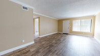 This single-floor residence offers a thoughtfully designed layout with warm, cohesive finishes throughout. The spacious main living area immediately impresses with its rich wood-look tile flooring, crisp white crown molding, and a textured ceiling that adds character. Warm beige walls create an inviting atmosphere, while a ceiling fan provides practical comfort. A front entry door with a sidelight window allows natural light to filter into the space.

The open living area flows seamlessly toward the kitchen, which is well-equipped with warm-toned wood cabinetry, granite countertops, a decorative mosaic tile backsplash, a stainless steel double-basin sink, and a stainless steel dishwasher. The kitchen's finishes are consistent and refined, offering both style and functionality.

The bedroom is generously sized, featuring the same wood-look tile flooring, a ceiling fan, and two side-by-side closets with bi-fold doors, providing ample storage. An en-suite bathroom is accessible directly from the bedroom and features a single vanity with granite countertops, rich wood cabinetry, a framed mirror, and a tiled tub-shower combination with a decorative accent border. The flooring in the bathroom continues the wood-look tile theme, tying the space together cohesively throughout.