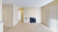 Located at 2515 Potomac Hunt Ln in Henrico, Virginia, this single-floor, one-bedroom, one-bathroom residence offers a well-organized layout across a compact yet efficient floor plan. The living room serves as the heart of the home, highlighted by a classic tile-surround fireplace with glass doors and soft carpeting underfoot. A sliding glass door with vertical blinds fills the space with natural light and provides access to the outdoors. Adjacent to the living area, the dining space features tile flooring and chair-rail molding, adding a subtle architectural detail to the neutral, warm-toned walls. The kitchen is outfitted with warm wood cabinetry, granite-style countertops, a double-basin stainless steel sink, and a full-size refrigerator, offering functional storage and workspace. The bedroom is a comfortable, light-filled retreat with plush carpet, a large window with blinds, and direct access to a dedicated closet. The full bathroom includes a single-vanity with wood cabinetry, a white countertop, a wall-mounted mirror, and a full-size soaking tub with shower combination featuring a safety grab bar. Throughout the home, consistent warm beige tones and clean white trim create a cohesive and inviting ambiance.