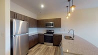 Located at 626 Lehman St in Columbus, Ohio, this single-floor residence offers a thoughtfully designed layout with modern finishes throughout. The entry opens directly into a well-appointed kitchen, which serves as a visual centerpiece with rich, dark wood-grain cabinetry, granite-style countertops, a white subway tile backsplash, and a full suite of stainless steel appliances including a refrigerator, electric range, and over-the-range microwave. Light wood-look flooring runs through the kitchen and common areas, complemented by stylish pendant lighting above the sink peninsula. The bedrooms feature plush wall-to-wall carpeting and ceiling fans, with multiple windows fitted with white blinds that invite generous natural light. The primary bedroom includes multiple closets, providing ample storage. Additional bedrooms are well-sized with their own windows offering exterior views. The bathrooms are finished with granite-top vanities featuring dark wood cabinetry, wood-look tile flooring, and clean white fixtures; one bathroom includes a full soaking tub and shower combination. Neutral warm tones on the walls throughout create a cohesive and inviting atmosphere, making this a well-balanced, move-in-ready residence in the heart of Columbus.