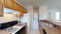 Located at 100 Park Boulevard in Cherry Hill, NJ, this two-floor residence offers a well-organized and functional living environment designed for everyday comfort. The kitchen serves as a central highlight of the home, featuring warm honey-toned wood cabinetry that provides generous storage space, granite-look countertops, and a full suite of appliances including a gas range with a black oven, a full-size refrigerator, and a stainless steel sink. A range hood is installed above the cooktop for ventilation, complementing the practical design of the space. Light tile flooring runs through the kitchen, contributing to a clean and easy-to-maintain aesthetic. A notable convenience of this residence is the in-unit stacked washer and dryer, tucked neatly into a dedicated alcove within the kitchen area, eliminating the need for shared laundry facilities. The textured ceiling adds a classic finish consistent throughout the space. Spanning two floors, the home offers a natural separation between living and private areas, providing both functionality and a sense of spaciousness. The overall design reflects a straightforward, comfortable layout suited for a variety of lifestyles in the well-established Cherry Hill community.