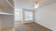 This single-floor, 2-bedroom, 2-bathroom residence offers a clean and functional layout designed for comfortable everyday living. The living and dining areas are finished with warm neutral-toned carpet and feature crown molding, ceiling fans, and multiple windows dressed with blinds that allow ample natural light to flow through the space. A glass-panel door provides access to the exterior, offering views of the surrounding area.

The kitchen is well-appointed with granite-style countertops, white cabinetry trimmed in warm wood tones, a full suite of white appliances including an electric range and dishwasher, and hardwood-style flooring. A peninsula counter connects the kitchen to the adjacent living area, making it ideal for casual dining or meal preparation.

Both bedrooms are spacious, carpeted, and fitted with ceiling fans. The primary bedroom includes a closet with a built-in rod and direct access to one of the two bathrooms. Each bathroom features a soaking tub and shower combination with white tile surround and chrome fixtures, delivering a clean, classic aesthetic throughout. The overall design is neutral and bright, providing a versatile canvas suited to a variety of interior styles.