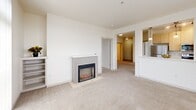 Located at 436 Broadway in downtown Tacoma, WA, this 2-bedroom, 3-bathroom residence offers a well-organized single-floor layout with a clean, modern aesthetic throughout. The bright living room is a standout, featuring plush carpeting, large sliding glass doors and windows that frame urban views of the Tacoma skyline, and a built-in fireplace that serves as a warm focal point. An adjacent galley-style kitchen is outfitted with light wood cabinetry, white countertops, stainless steel appliances including a range and dishwasher, and a window overlooking the cityscape. Both bedrooms are carpeted and finished with neutral tones, offering a calm and restful atmosphere. Each bedroom includes a sliding-door closet with built-in racking. The primary bedroom benefits from large windows with elevated city views and a baseboard heating system. The three bathrooms are consistent in their clean, white finishes, each featuring a tub-shower combination with curved chrome curtain rods, wood-toned flooring, a single-basin vanity with white countertop, and well-lit mirrors. Accessibility-friendly grab bars are present in at least one bathroom. The overall design is understated and functional, with abundant natural light and urban views throughout.