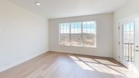 Located at 9 Monticello Dr in Brewster Village, NY, this thoughtfully designed one-bedroom, one-bathroom residence offers a clean, contemporary aesthetic with high-quality finishes throughout. Light hardwood flooring flows seamlessly across the entire unit, complementing the bright white walls and recessed lighting that give every room an open, airy feel.

The open-concept kitchen and living area serves as the heart of the home. The kitchen is outfitted with light wood cabinetry accented by gold hardware, quartz countertops with marble-like veining, a white subway tile backsplash, and a full suite of stainless steel appliances. A center island with an undermount sink and globe pendant lighting above makes for a functional and stylish focal point, flowing naturally into the spacious living area.

Multiple large double-hung windows frame panoramic views of the surrounding wooded landscape, filling the living spaces with abundant natural light throughout the day. A private balcony access adds an outdoor dimension to the living area.

The bedroom is a well-proportioned retreat with a wide picture window overlooking the natural scenery, a dedicated closet, and continued hardwood flooring. The bathroom features floor-to-ceiling porcelain tile surrounding a soaking tub and shower combination, paired with wood-toned cabinetry and a wide vanity mirror. A hallway connects all spaces efficiently, completing this well-appointed residence.