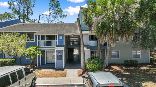 Charming apartment exterior with lush palm trees, ample parking, and welcoming ambiance in a serene setting. - Vista North