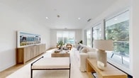 Located at 402 Halstead Ave in Harrison, NY, this thoughtfully designed single-floor residence offers three bedrooms and four bathrooms within a well-appointed, open-concept layout. Light-toned hardwood flooring runs throughout, complementing a clean, contemporary aesthetic defined by crisp white walls and recessed lighting.

The living area is expansive and sun-drenched, featuring large sliding glass doors and oversized windows that frame lush outdoor greenery. A glass-railed balcony extends the living space outward, offering serene tree-canopy views. The kitchen is sleek and modern, boasting white cabinetry, a large center island with bar seating, pendant lighting, stainless steel appliances, and a wall of windows that floods the space with natural light.

The primary bedroom is a peaceful retreat with neutral tones and direct access to well-organized closet space. Eight total closets — including generously sized walk-ins with custom shelving systems — provide exceptional storage throughout the home. The four bathrooms are finished with marble-style tile flooring and modern chrome fixtures.

Wide, light-filled hallways connect the rooms effortlessly, and a dedicated laundry area adds everyday convenience. The home's modern design, abundant storage, and seamless indoor-outdoor connection make it a highly functional and welcoming living space.